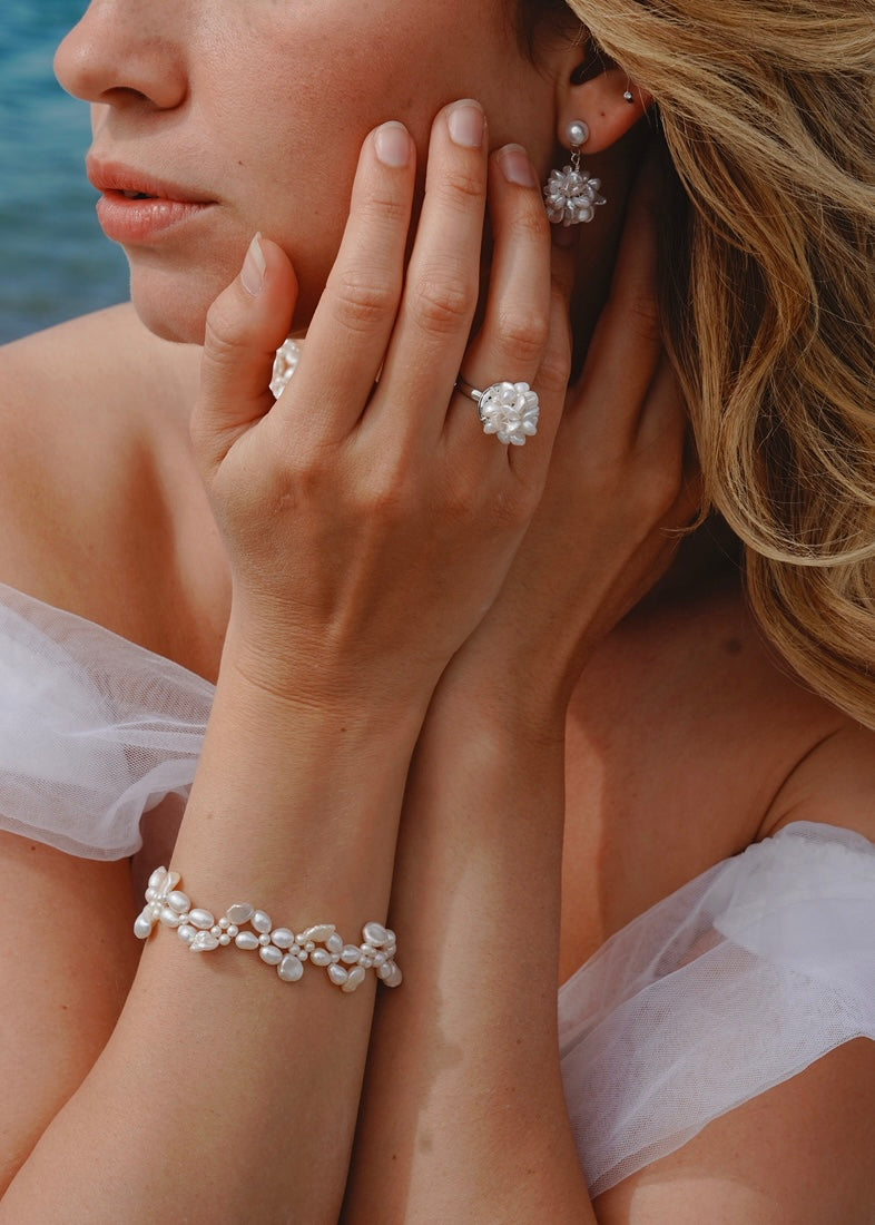 Close-up of a woman wearing pearl jewelry with a blurred natural background