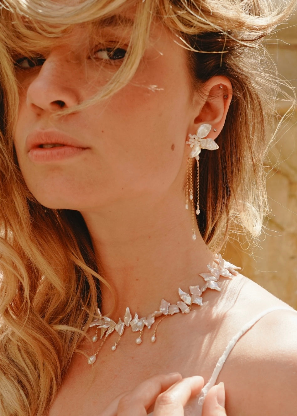 Close-up of a woman wearing delicate floral jewelry with a blurred background