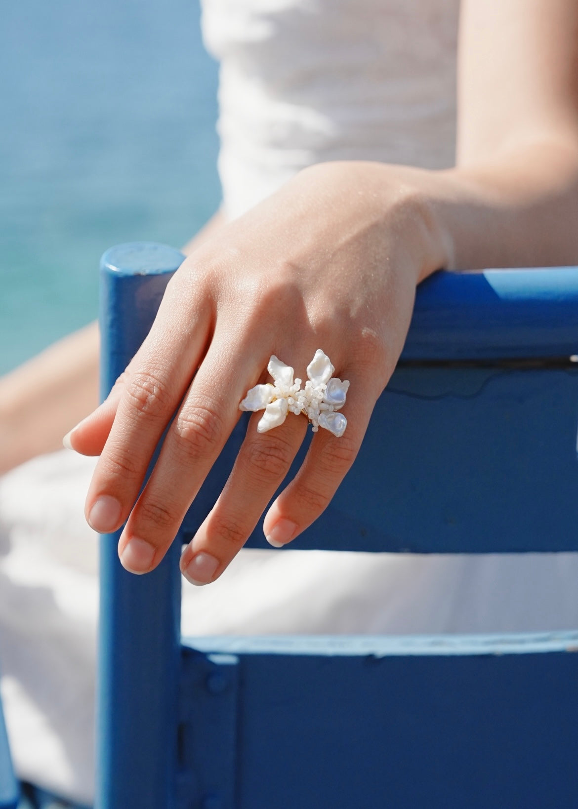 Hand wearing a decorative ring on a blue chair with a blurred background