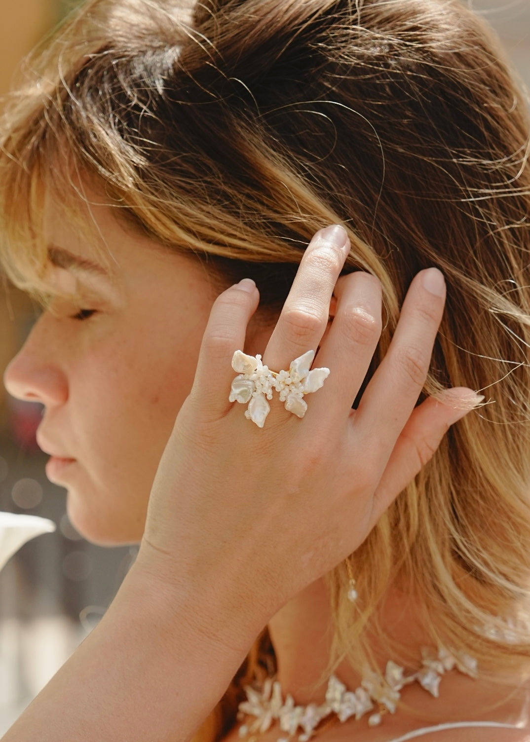 Close-up of a person wearing a delicate floral ring with blurred background