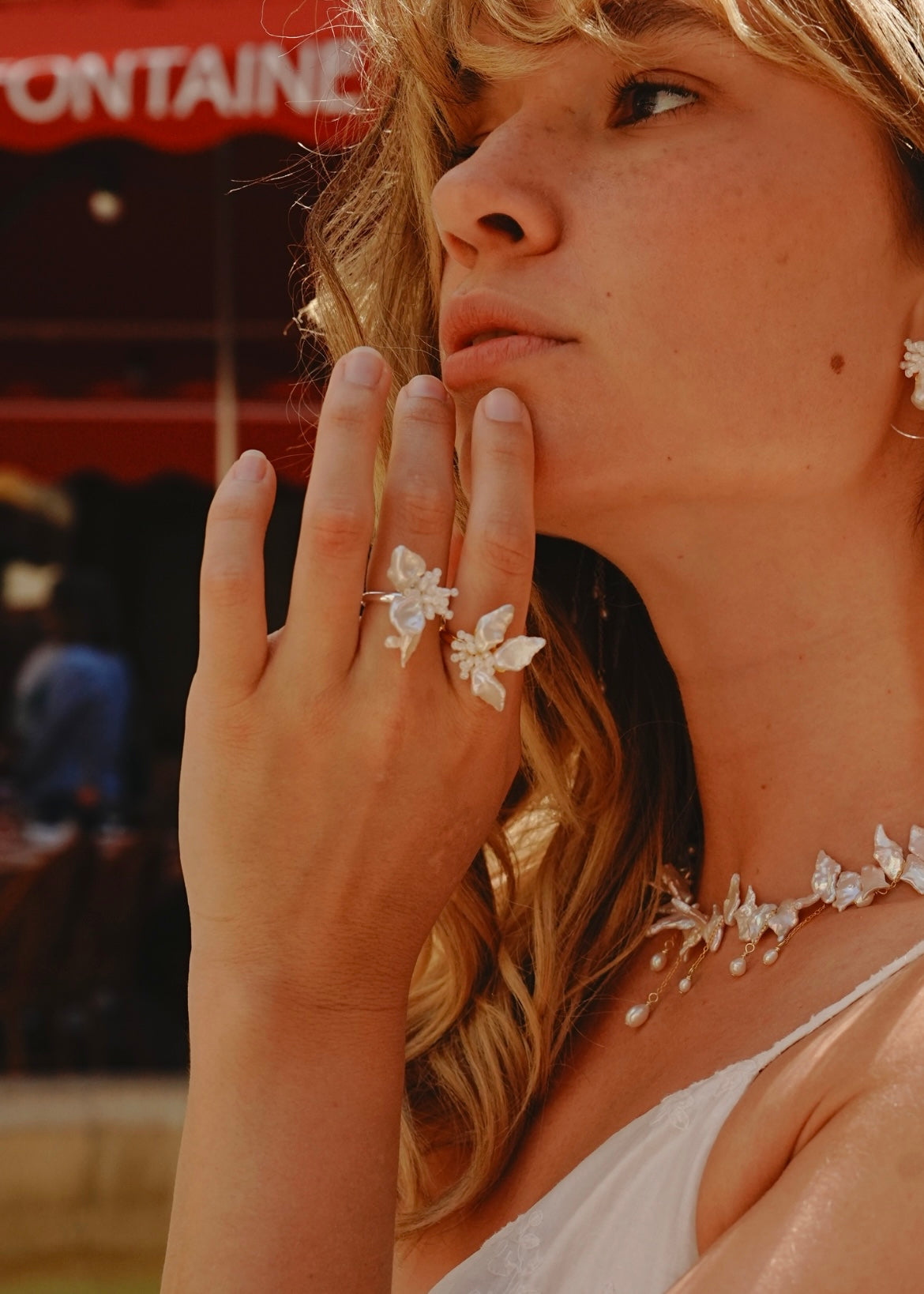 Woman wearing a floral ring and necklace with a blurred background