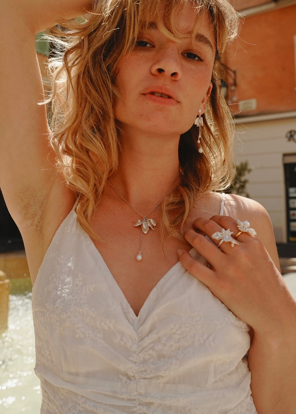 Woman wearing a white dress with petal drops pearl necklace outdoors