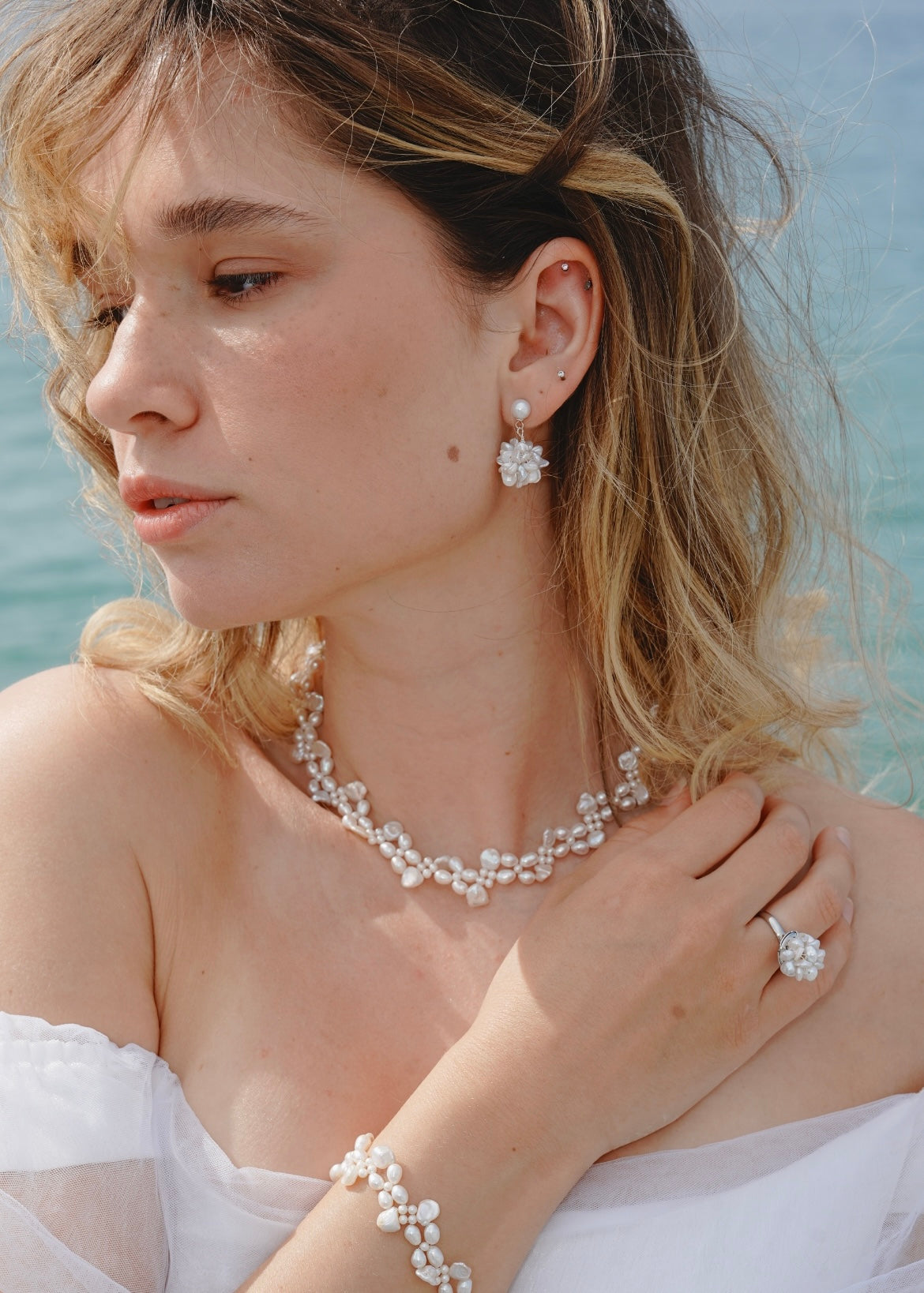 Woman wearing pearl jewelry with a blurred natural background