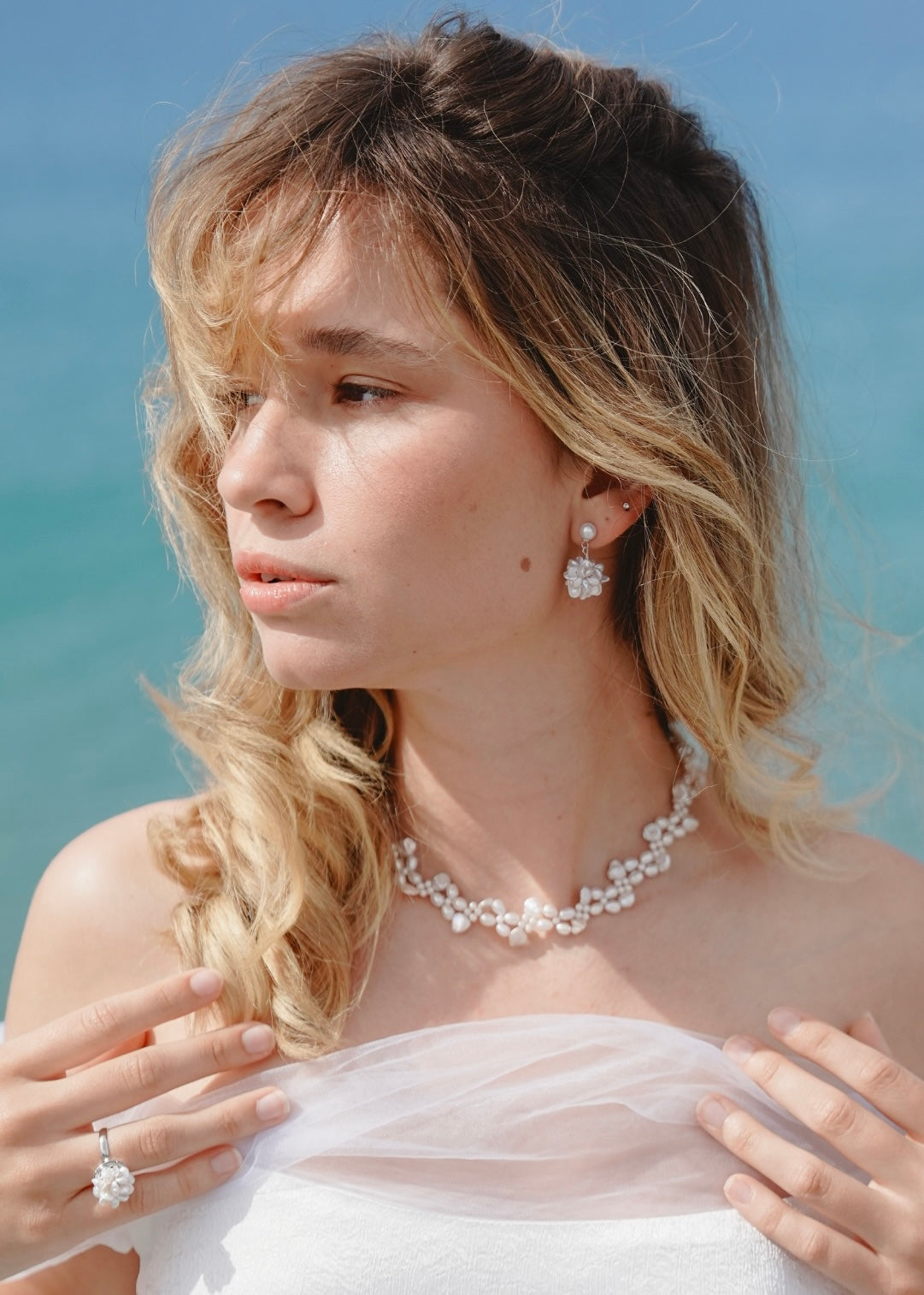 Woman wearing a pearl necklace and earrings with a blurred background