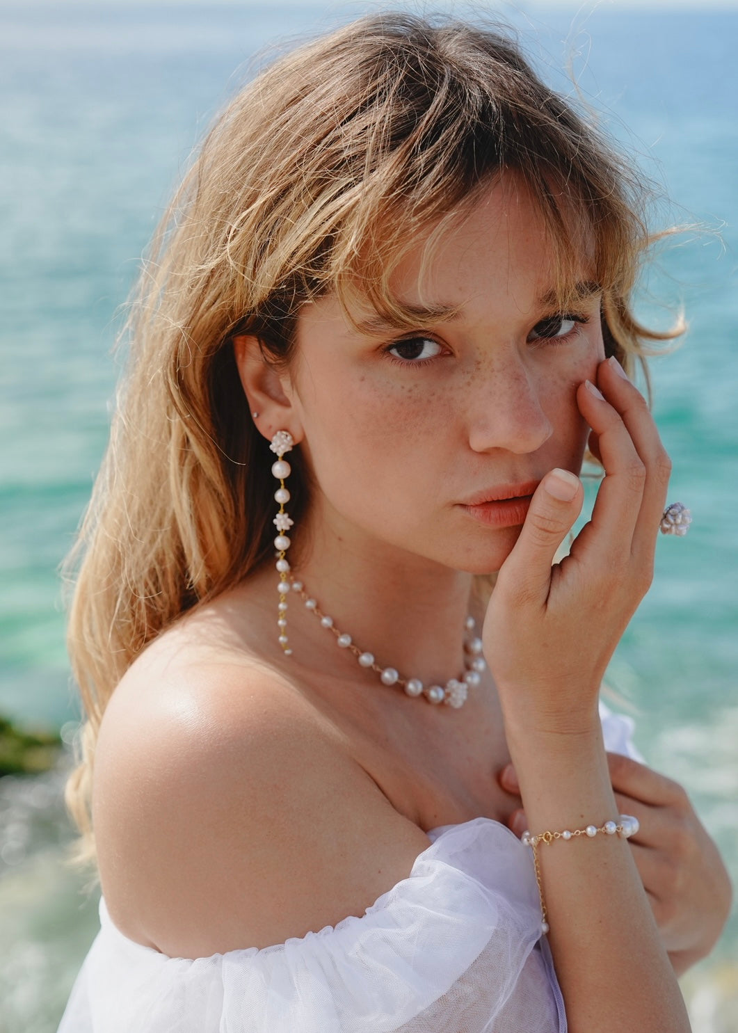 Woman with pearl jewelry by the sea
