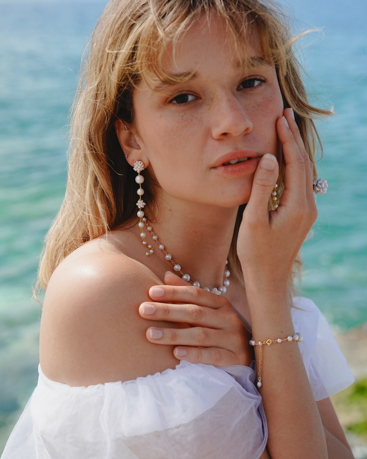 Woman wearing pearls with a blurred ocean background