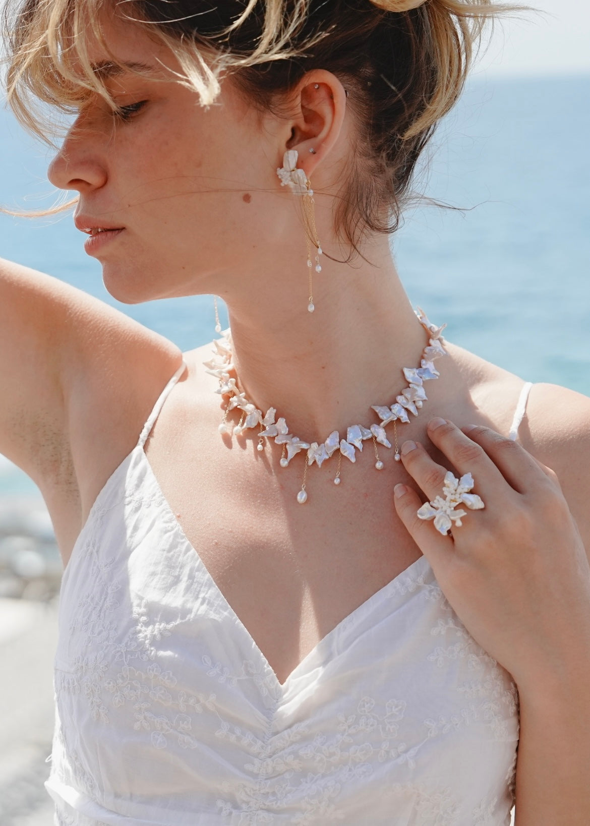 Woman wearing a floral necklace and earrings with a blurred beach background